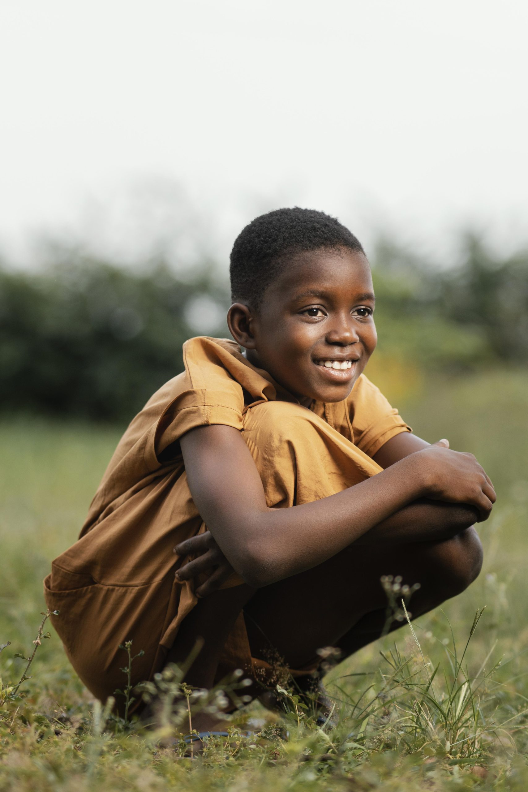 smiley young african boy standing field